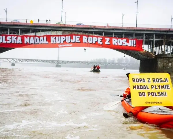 Na moście Poniatowskiego wisi czerwony baner "Polska nadal kupuje ropę z Rosji!". Kajakarz Greenpeace na Wiśle trzyma żółtą tablicę "Ropa z Rosji nadal płynie do Polski".