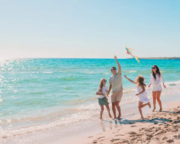 Rodzina puszcza latawiec na plaży. Idealne fajne miejsce na wakacje z dzieckiem w Polsce.