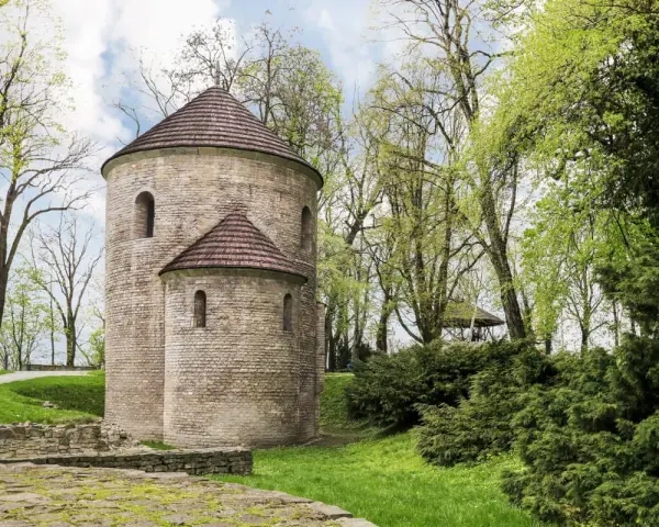 Kamienna rotunda, najstarszy kościół w Polsce, otoczona zielenią.
