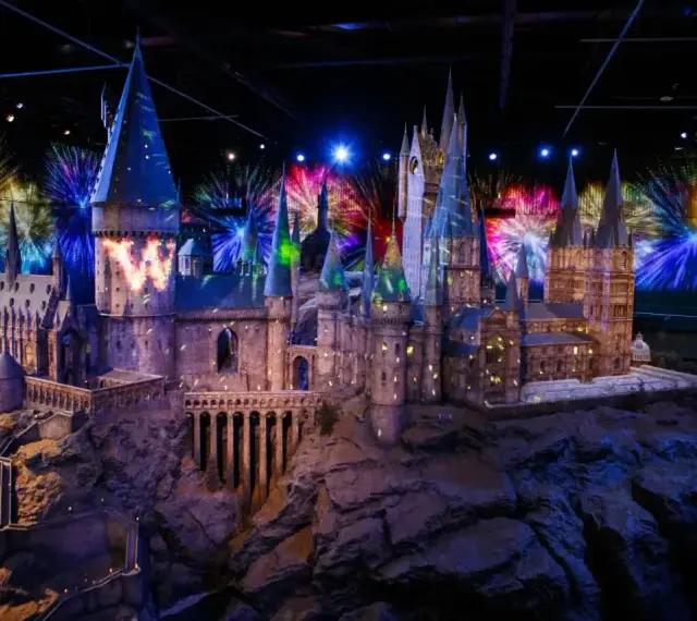 Model zamku Hogwart w muzeum Harry'ego Pottera, oświetlony magicznymi projekcjami i fajerwerkami.