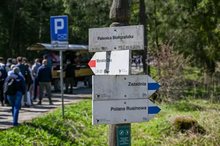 Drewniany drogowskaz w górach z nazwami szlaków: Palenica Białczańska, Morskie Oko, Zazadnia, Polana Rusinowa.