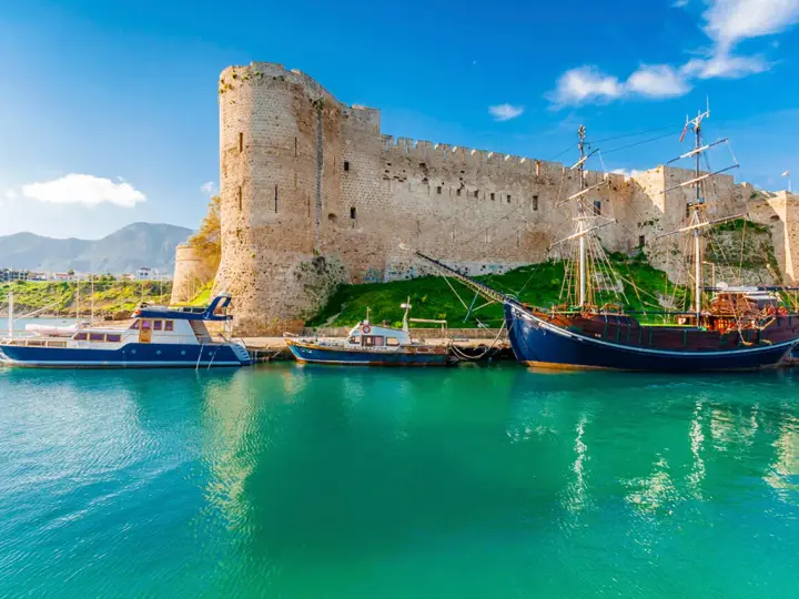 Zamek Kyrenia na Cyprze Północnym z łodziami przycumowanymi w turkusowej zatoce.