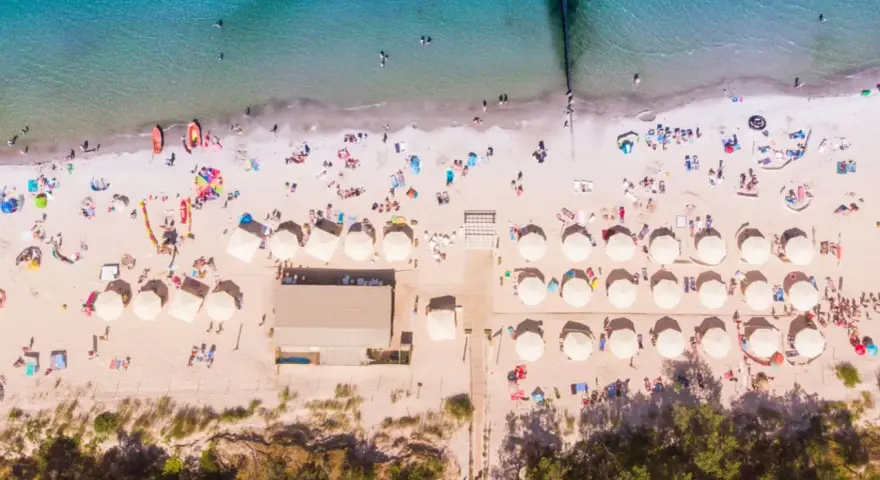Plaża z parasolami i ludźmi, idealna na wakacje all inclusive Polska.