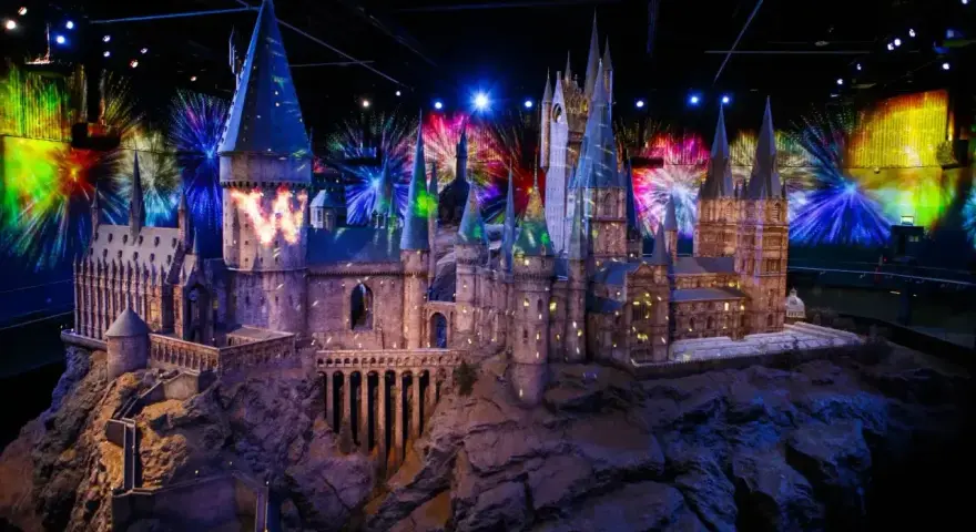 Model zamku Hogwart w muzeum Harry'ego Pottera, oświetlony magicznymi projekcjami i fajerwerkami.
