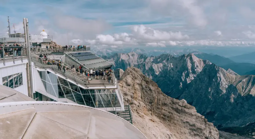 Tłum turystów na tarasie widokowym Zugspitze, najwyższego szczytu Niemiec, podziwia alpejskie krajobrazy.