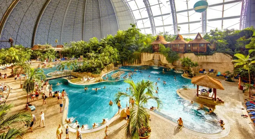 Wielki tropikalny basen pod kopułą, z palmami, wodospadami i domkami. Sprawdź nasz tropical island cennik, by zaplanować wakacje!