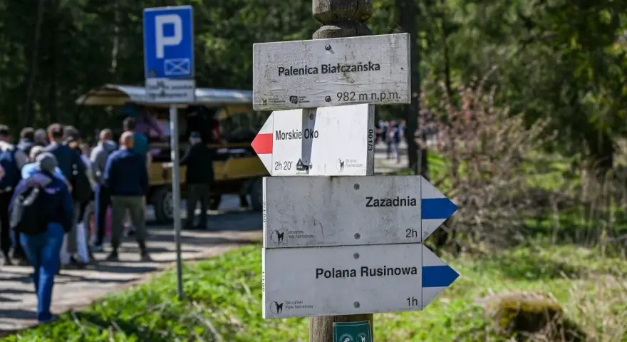 Drewniany drogowskaz w górach z nazwami szlaków: Palenica Białczańska, Morskie Oko, Zazadnia, Polana Rusinowa.