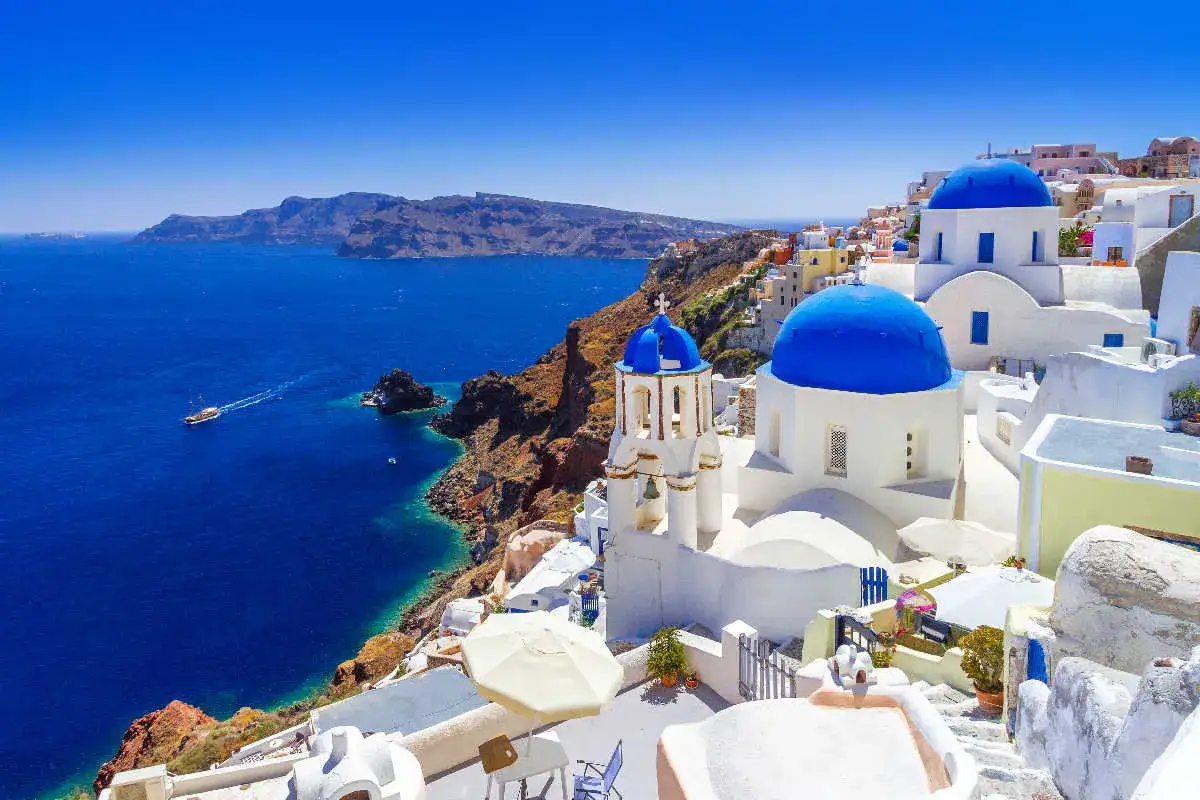 Santorini wakacje: białe domy z niebieskimi kopułami kościołów na klifie nad lazurowym morzem.