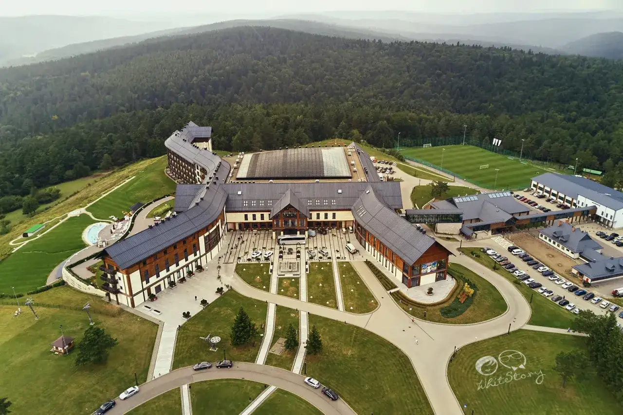 Hotel Arłamów, dzieło właściciela, w otoczeniu zielonych wzgórz. Widok z lotu ptaka na architekturę i infrastrukturę kompleksu.