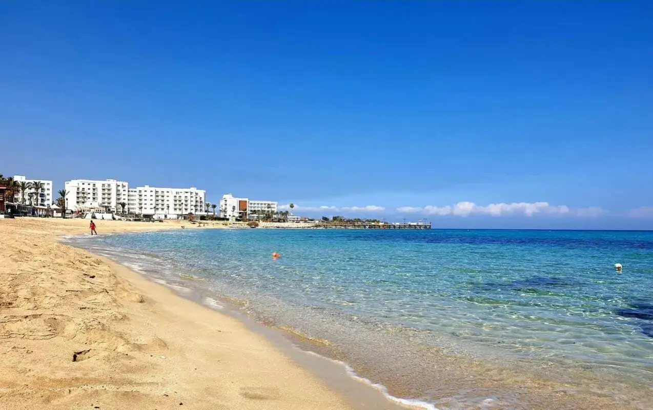 Piękna plaża w Protaras na Cyprze. Czysta, turkusowa woda i białe hotele w tle tworzą idealne wakacyjne marzenie.