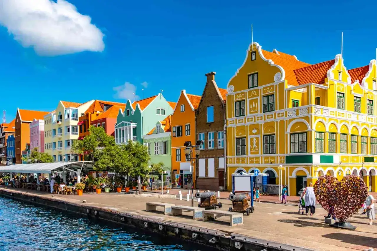Kolorowe kamienice nad wodą, idealne na wakacje na Curacao. Słoneczny dzień, turkusowa woda i zabytkowe działa tworzą niepowtarzalny klimat.