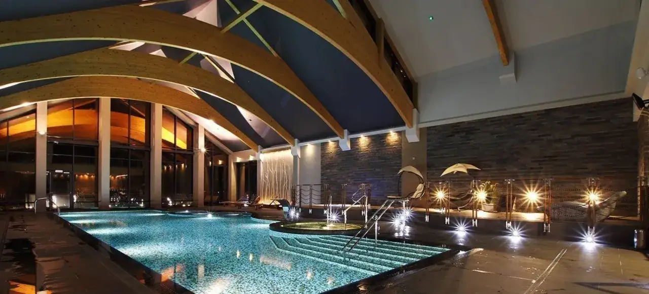 Luksusowy basen w hotelu dla dorosłych, z podświetlanymi schodkami i jacuzzi.