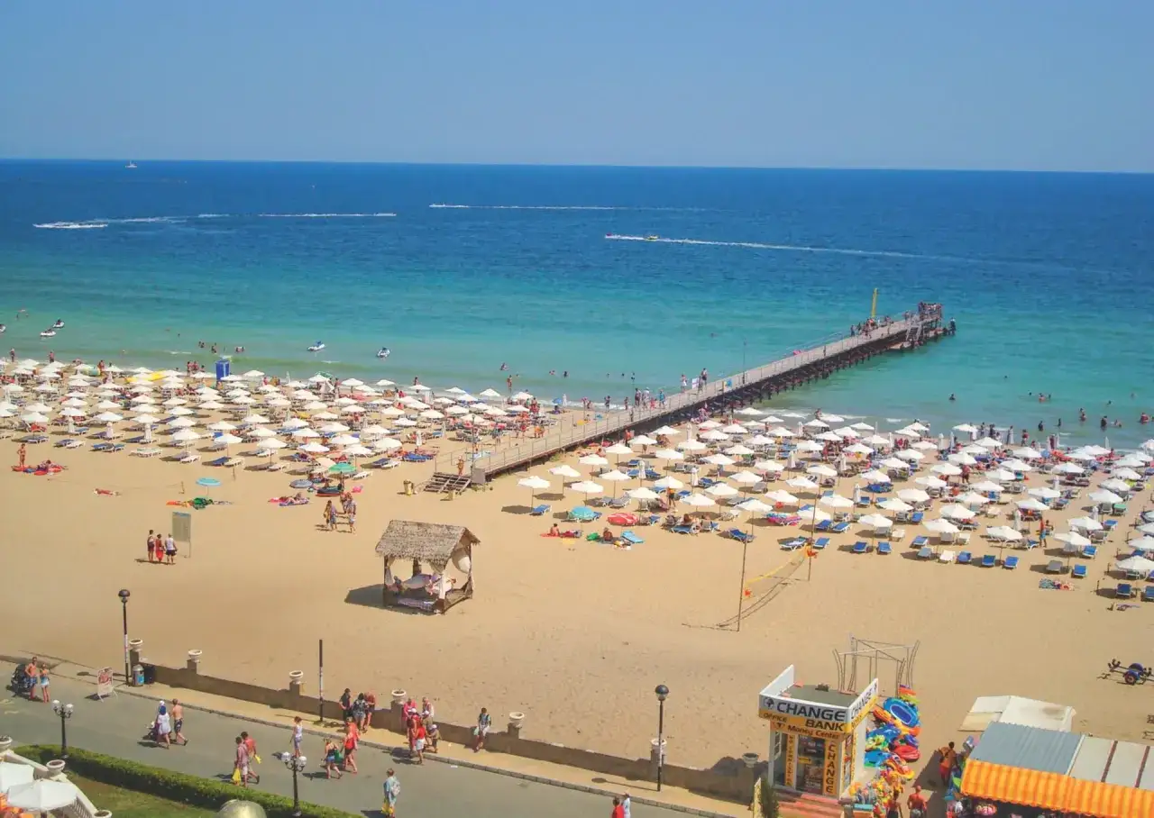Słoneczny Brzeg, Bułgaria: Tłoczna plaża z białymi parasolami, molo i turkusowe morze.