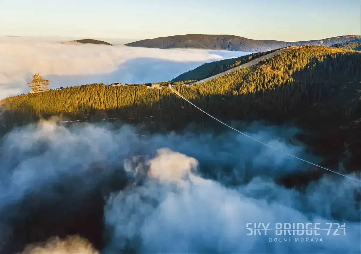 Widok na najdłuższy most w Czechach, Sky Bridge 721 w Dolní Moravie, zawieszony nad morzem chmur i otoczony lasami.