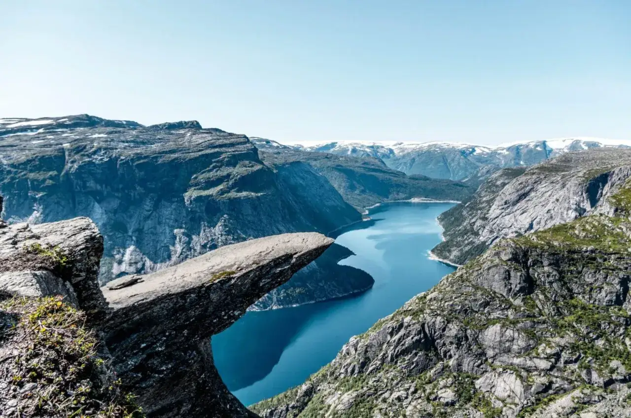 Niesamowite fiordy Norwegii z wiszącą skałą Trolltunga. Błękitna woda jeziora otoczona skalistymi górami.