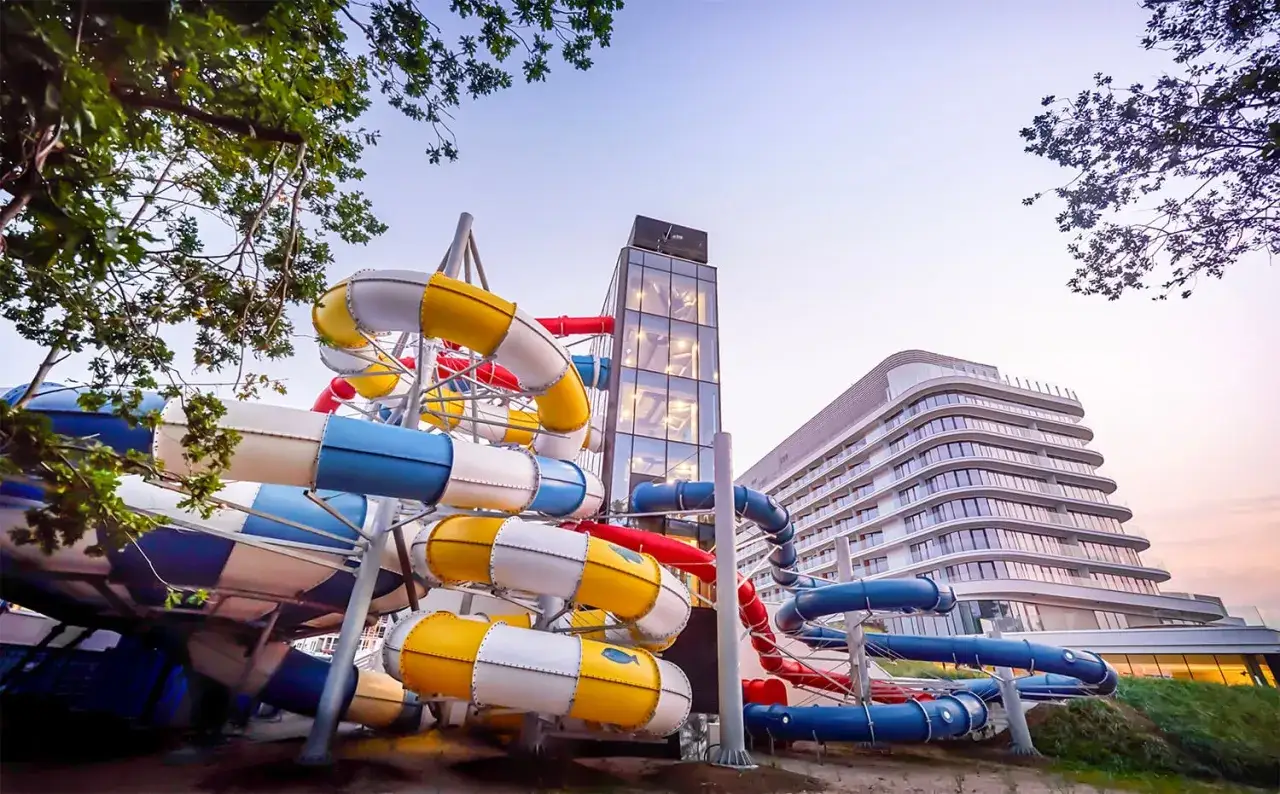 Kolorowe zjeżdżalnie wodne przy nowoczesnym hotelu z aquaparkiem, zapraszają do zabawy.