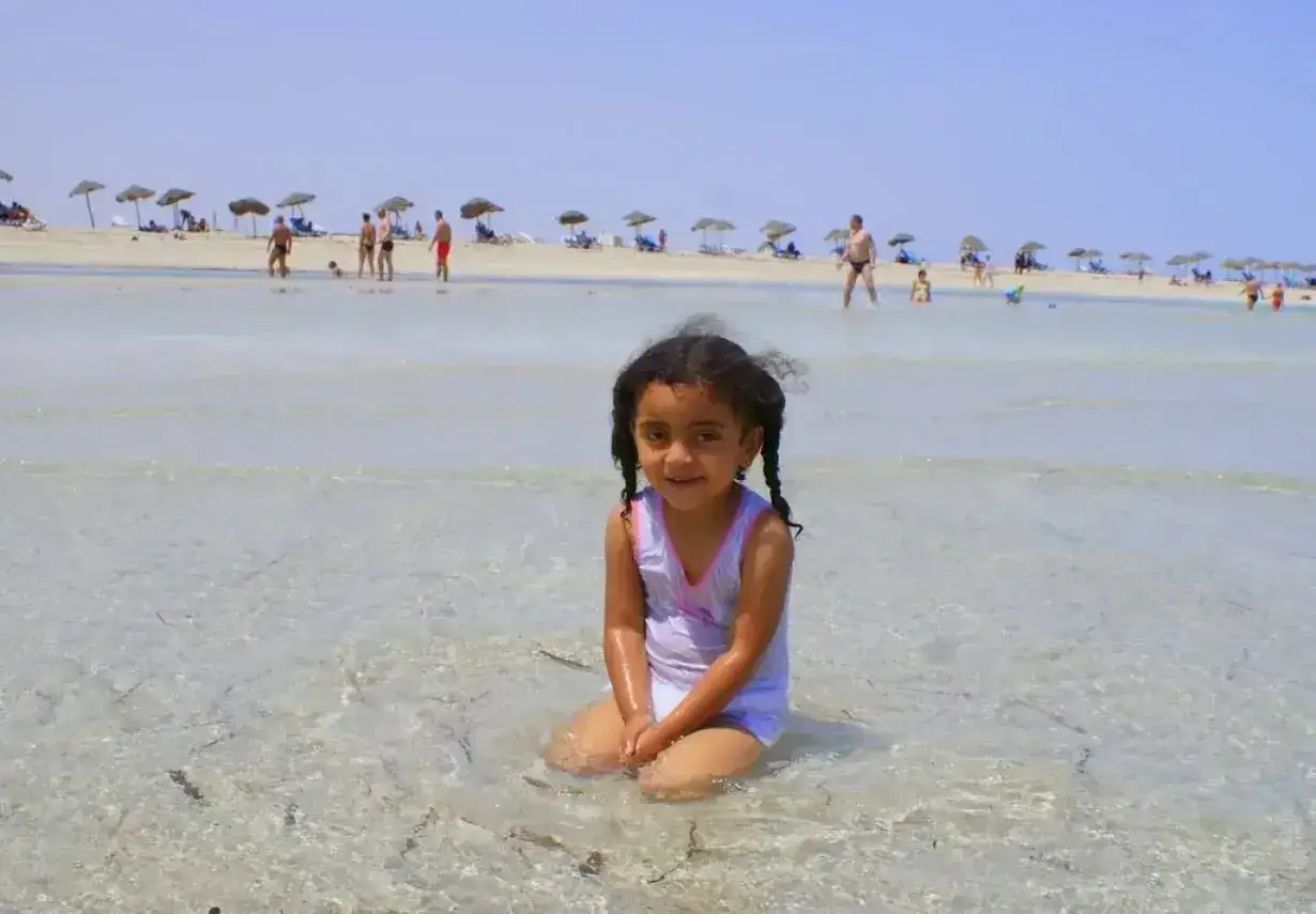 Djerba na co uważać? Słoneczna plaża, płytka woda i uśmiechnięta dziewczynka. Uważaj na słońce i ciesz się wakacjami!
