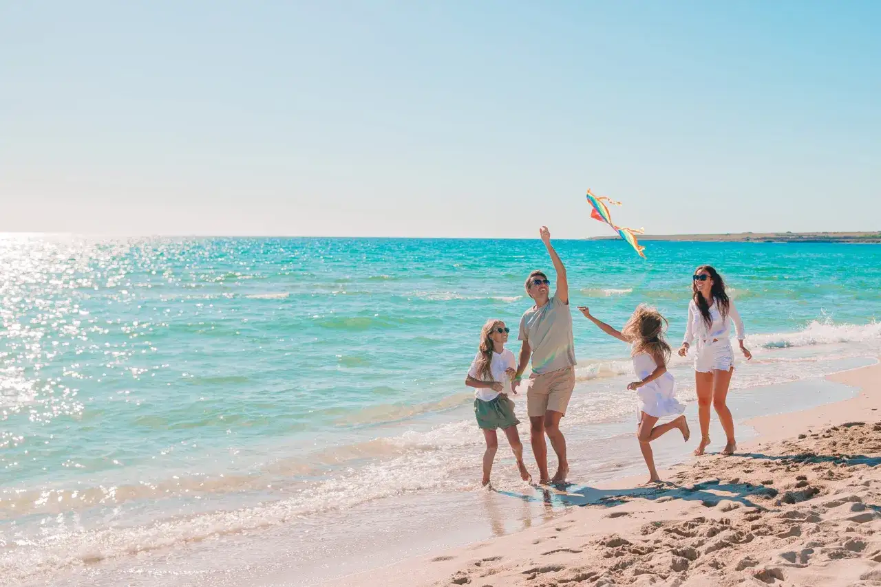 Rodzina puszcza latawiec na plaży. Idealne fajne miejsce na wakacje z dzieckiem w Polsce, gdzie słońce i morze tworzą niezapomniane wspomnienia.