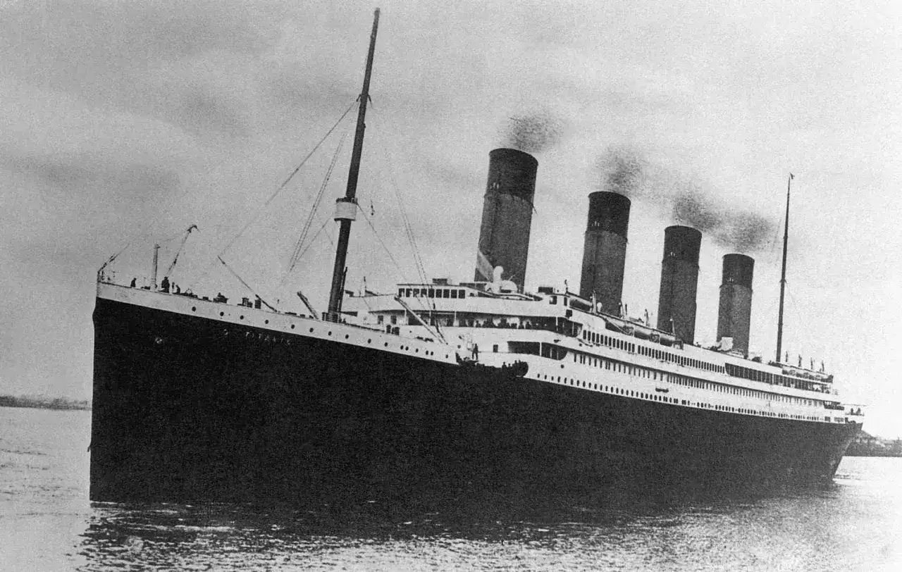Ogromny statek RMS Titanic, dymiący z kominów, wypływa na spokojne wody.