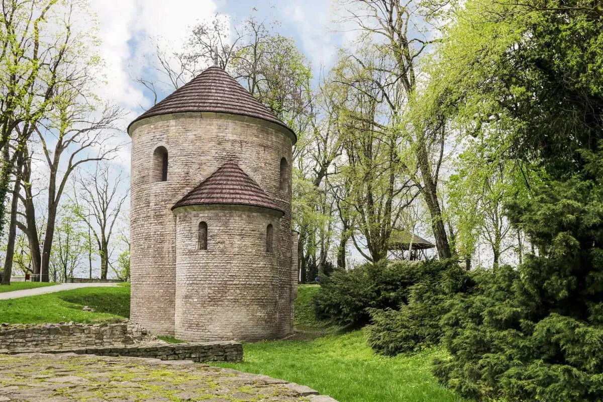 Kamienna rotunda, najstarszy kościół w Polsce, otoczona zielenią.
