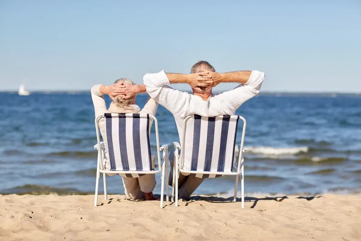 Para seniorów relaksuje się na plaży, ciesząc się słońcem i morzem. Idealne wczasy dla seniora 7 dniowe.