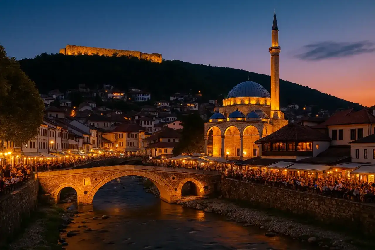 Wieczorny widok na Prizren, miasto w najmłodszym państwie Europy, z oświetloną twierdzą na wzgórzu, meczetem i tętniącym życiem mostem.