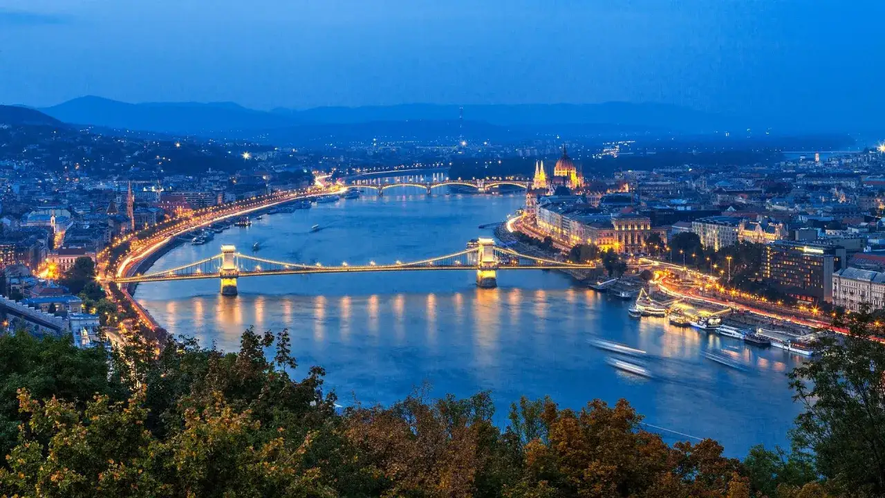 Nocny widok na rzekę w Budapeszcie, z oświetlonymi mostami i budynkami.