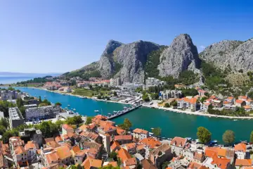 Widok na miasto Omiš w Chorwacji, gdzie rzeka Cetina wpada do morza. Piękne, turkusowe morze i góry.
