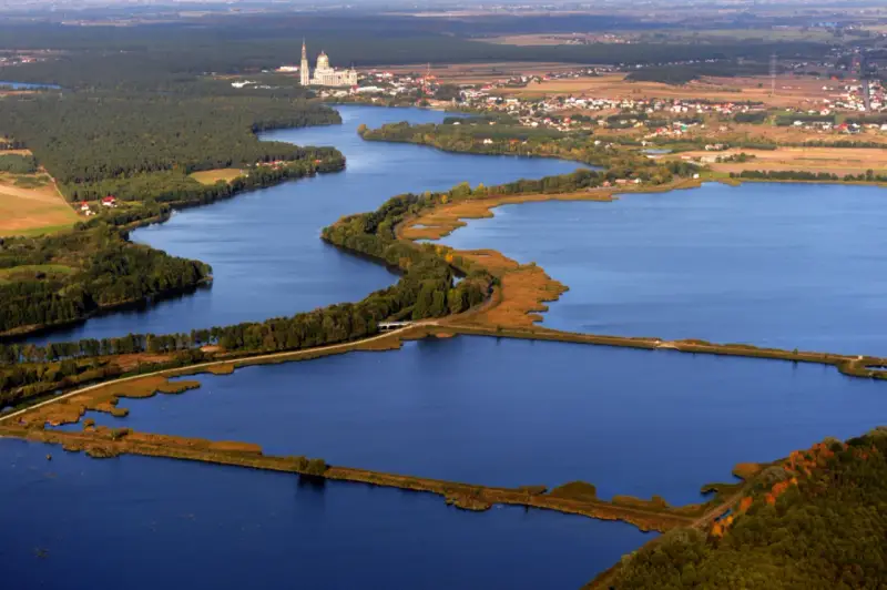 Widok z lotu ptaka na jezioro z wyspami, lasami i zabudowaniami w tle.