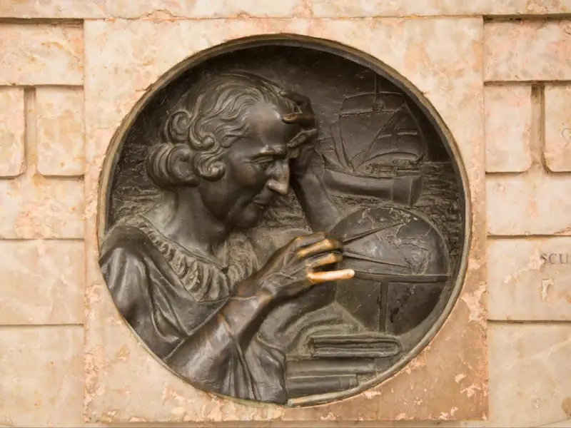 Krzysztof Kolumb, badający mapy i globus, symbolizuje jego pochodzenie i dążenie do odkryć. W tle żaglowiec.
